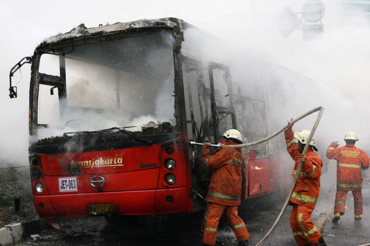 Firefighters extinguish a fire on a Transjakarta bus at the Hotel Indonesia traffic circle in 2012. Just like any new system, the Transjakarta is not without its faults.