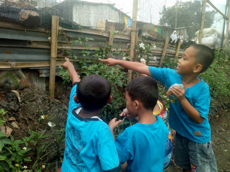 Anak-anak mengamati seekor terung hitam, putih dan oranye, spesies kupu-kupu, yang bertengger di atas sebuah tanaman di Taman Kupu-kupu di Cipinang Melayu, Kecamatan Makassar, Jakarta Timur, pada hari Senin. Enklosur 120 meter persegi adalah bagian dari ruang terbuka hijau Cipinang Melayu. (JP / Sausan Atika)