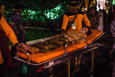 A guest lies on a stretcher as she waits for medical help after fainting while standing in line. JP/Anggertimur Lanang Tinarbuko