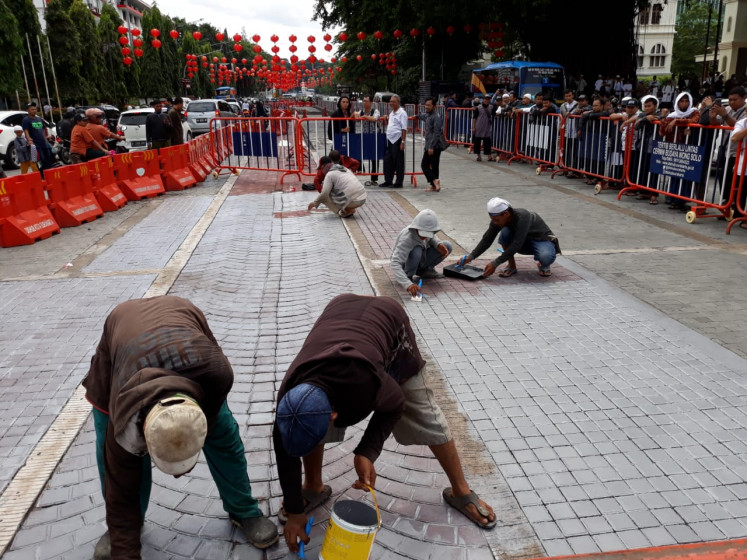 Workers paint over a road mosaic in front of the Surakarta City Hall in Central Java after Muslims groups complained that the street art resembled a Christian cross.