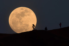In this file photo taken on January 30, 2018, a person poses for a photo as the moon rises over Griffith Park in Los Angeles, California. 