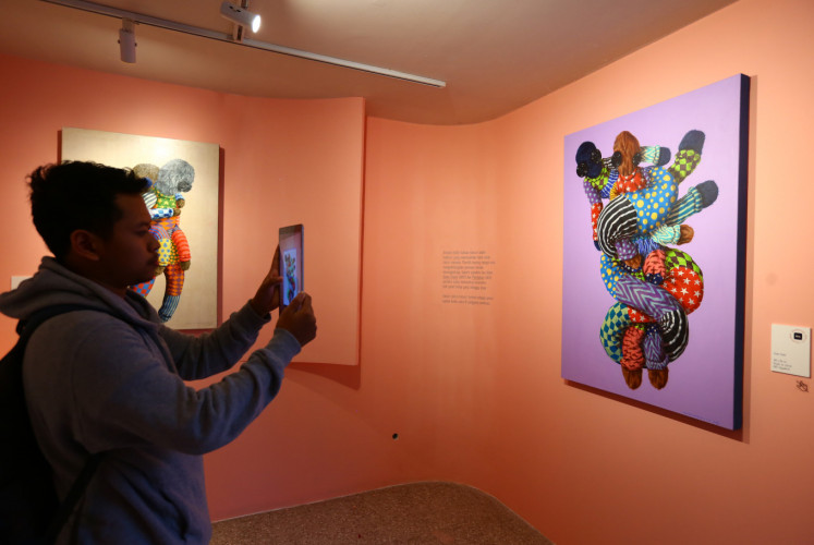 A visitor stands before the 'Green Snake' painting and tries out augmented reality (AR) at the 'Kaum Mata Kancing' exhibition by I Putu Adi 'Kencut' Suanjaya on Friday, Jan. 18 at Kopi Kalyan, South Jakarta.