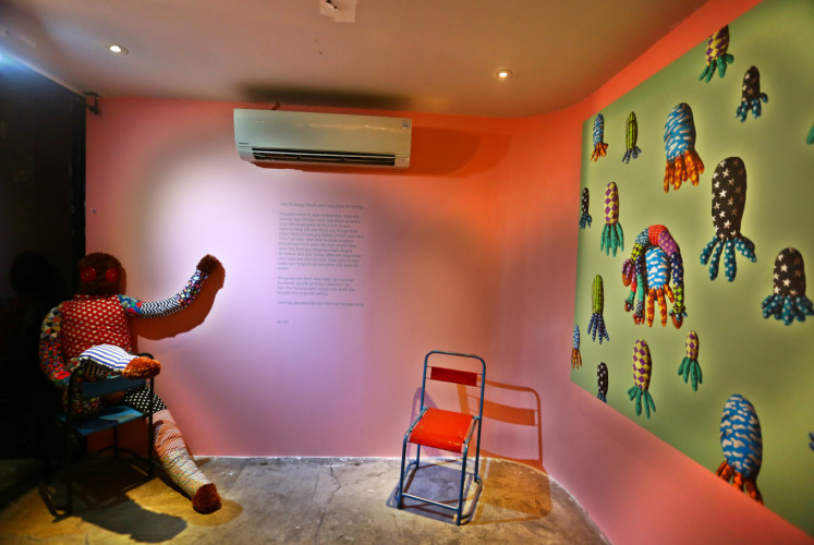 A 3-dimensional doll of a button-eyed figure (left) and 'Repetition Series (3)' painting (right) at the 'Kaum Mata Kancing' exhibition by I Putu Adi 'Kencut' Suanjaya on Friday, Jan. 18 at Kopi Kalyan, South Jakarta.
