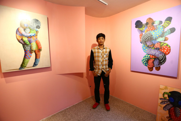 Yogyakarta-based artist I Putu Adi 'Kencut' Suanjaya poses between his artwork at 'Kaum Mata Kancing' exhibition by I Putu Adi 'Kencut' Suanjaya on Friday, Jan. 18 at Kopi Kalyan, South Jakarta.