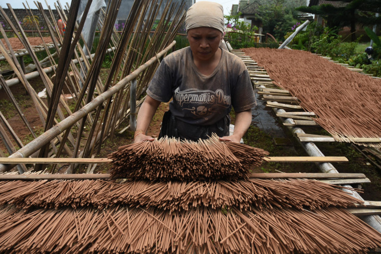 A woman works at a traditional incense stick factory in Malang, East Java on Feb. 2, 2018.