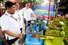 Jakarta Police special crimes investigators inspect confiscated canisters of liquefied petroleum gas (LPG) on Feb. 4, 2025, on the premises of a distributor in Cilangkap, East Jakarta. The business is suspected of purchasing 3-kilogram canisters of subsidized LPG to refill 12 kg canisters.