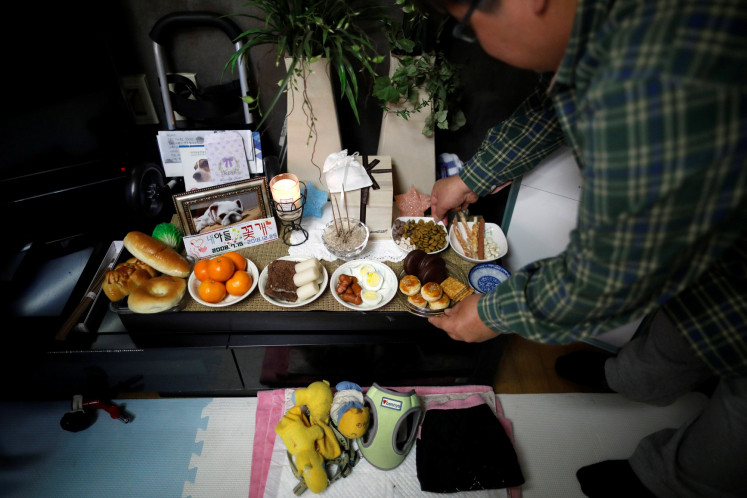 Lee Jae-hwan puts pet food on a memorial altar for his pet dog Kkotgae at his home in Namyangju, South Korea, January 10, 2019. 