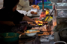 Basiran’s wife puts “kembang waru” doughs into the oven. JP/Boy T. Harjanto