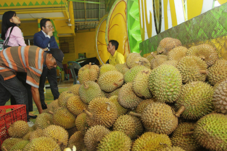 Indonesian customers sample durian fruits at a stall in Medan on January 30, 2019. 