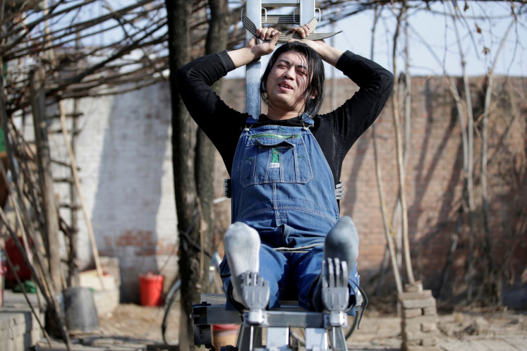 Geng Shuai poses on his invention 'happy chair', a workout bench with robotic arms to tickle the underarms and the feet, outside his workshop in Yangcun village of Baoding, Hebei province, China January 22, 2019.