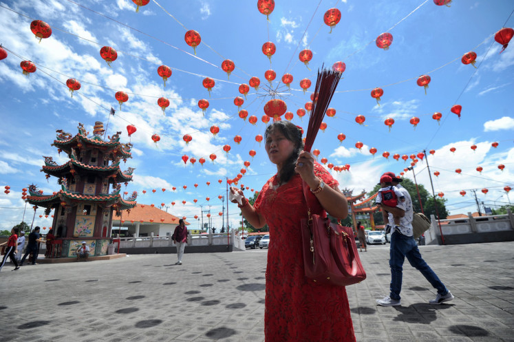 A woman carrying incense sticks arrives at a Chinese temple to pray on the first day of the Lunar New Year in Denpasar on Indonesia's resort island of island on Feb. 5, 2019