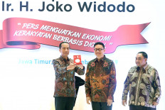 President Joko “Jokowi” Widodo (left), accompanied by Press Council chairman Yosep Adi Prasetyo (center) and the 2019 National Press Day’s (HPN) organizing committee head, Margiono, shows journalists the Press Freedom Award he received during the HPN celebration in Surabaya, East Java, in 2019.