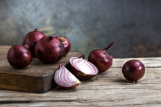 Red onions on a wooden board.