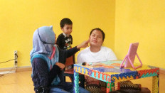 Against all odds: Aisyah Cahyu Cintya (left), who is a disability activist and has cerebral palsy, puts makeup on a woman at Rumah Harapan Indonesia. She paid a visit to motivate children and parents in the shelter to stay optimistic despite their disabilities and illnesses. 
