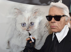German fashion designer, artist, and photographer Karl Lagerfeld poses next to a painting of his cat 'Choupette' during the inauguration of the show 'Corsa Karl and Choupette' at the Palazzo Italia in Berlin on February 3, 2015. 