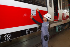 A rail worker places a sign on an LRT Jabodebek train car, made by state-owned train manufacturer PT Industri Kerata Api (INKA).
