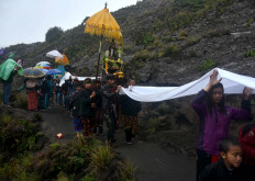 Villagers parade heirlooms and offerings on the way to the Widodaren spring while others hold sheets to catch the rain. JP/Aman Rochman