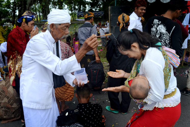 A 'pemangku' (Hindu priest) splashes holy water on one of the Melasti participants at the end of the ritual. 