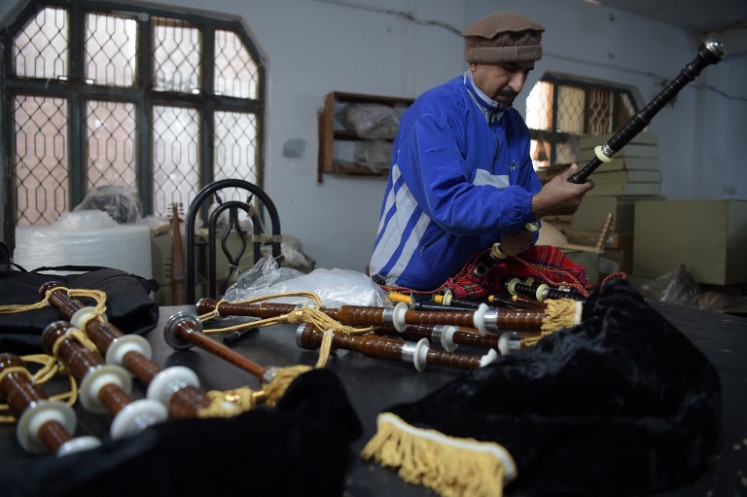 A Pakistani worker fixes a component to make a set of bagpipes at the Mid East bagpipe factory in the eastern city of Sialkot on January 25, 2019. 