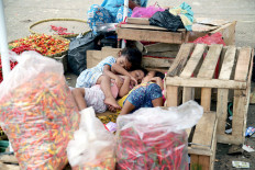 Children sleep against wooden crates near bags of chilies on March 1, 2021 at Kramat Jati Wholesale Market in East Jakarta. The increase in the price of bird's eye chilies was a contributing factor to a rise in the consumer price index (CPI) in February.
