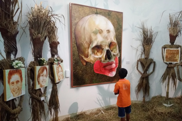 A boy gazes at a painting on displayed at the 'Memedi Sawah' exhibition at the Balai Soedjatmoko in Surakarta, Central Java. The exhibition, which artist Hari Budiono says is a form of resistance against the fear in the current political environment, runs through March 23.