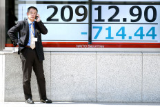 Pick up, please: A man stands in front of where the Tokyo Stock Exchange rate is displayed in a window of a security company in Tokyo on Monday. Tokyo was hammered 3 percent as the yen, which is considered a safe haven in times of turmoil, held on to Friday’s advance against the US dollar.
