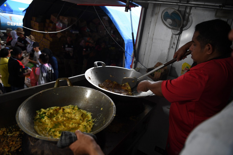 Volunteers cook meals at Tanah Merah shelter in Jayapura, Papua, on March 21. About 11,000 people in Jayapura fled their inundated homes following a flash flood on March 16.
