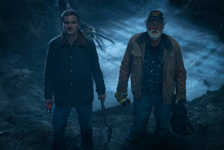 Accompanied by his neighbor Jud (John Lithgow, right), Louis (Jason Clarke, left) buries the family's dead cat on a misty hill. 