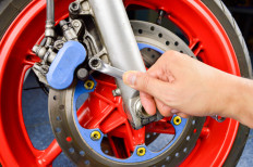 A motorcycle mechanic repairs brakes.