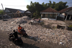 Motorists pass piles of waste on a villager’s front yard. JP/Sigit Pamungkas