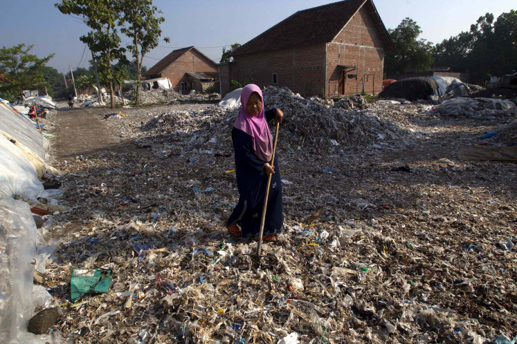 A woman dries waste in front of her house in Bangun village, Mojokerto, East Java.
