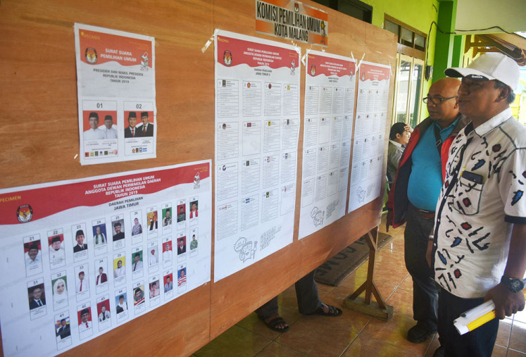 Two men study the list of 2019 general election candidates posted on a bulletin board outside the General Elections Commission (KPU) office in Malang, East Java. 