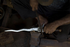 Shining silver: An iron file is used to refine intricate parts of a kris. JP/Sigit Pamungkas