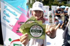 A volunteer encourages people at Car Free Day in Jakarta on Sunday to go to polling stations to vote in the legislative and presidential elections on April 17.