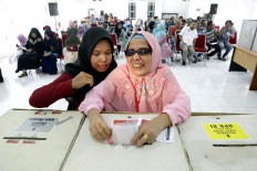 A blind woman is shown how to vote during an election day simulation in Aceh on April 14, 2019. 