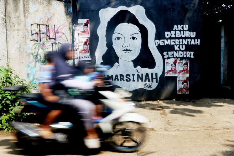 A motorbike rides past a mural of slain labor activist Marsinah at Babakan Pocis, South Tangerang, Banten, on Monday. Marsinah, then a worker at a watch factory in Sidoarjo, East Java, was killed on May 8, 1993, as she led a strike demanding better wages and working conditions.