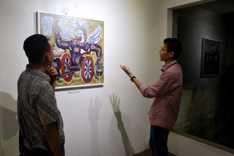 Jefri Chaniago (right) of Kiniko Art Management explains an artwork by Heri Dono to a visitor at the 