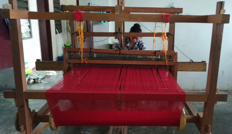 Quality tradition: A weaver uses a traditional floor loom to make  'ulos'.
