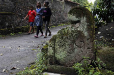 Children walk past a temple relief during their trip to Krapyak Cemetery to participate in the nyadran ritual in Jogonalan, Klaten, Central Java on April 28. JP/Magnus Hendratmo