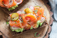 Danish open sandwich smorrebrod with salmon on rye bread with vegetables and herbs