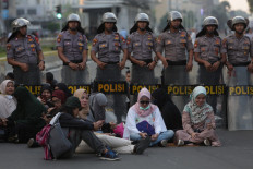 Election result protesters sit on the road at the Hotel Indonesia traffic circle in Jakarta on May 21 while riot police stand guard behind them. 