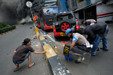 A young man helps policemen gather bullets from a police car damaged by rioters in Slipi, West Jakarta. JP/Jerry Adiguna