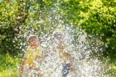 Two children pillow-fights each other at the park on a summer day