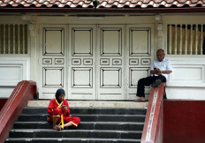 A teenage girl and an older man are busy with their mobile phones in front of Kauman mosque. JP/Boy T. Harjanto