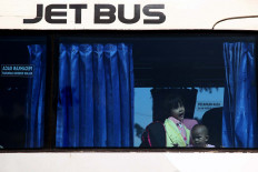 The wheels on the bus: Two children travel with their parents to their hometown from Kampung Rambutan Station in East Jakarta on Wednesday. Most of the homebound travelers departing from the bus station were women and children. JP/PJ Leo
