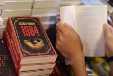 A boy reads a book next to copies of British writer George Orwell's '1984' at Hong Kong's annual book fair on July 15, 2015. 