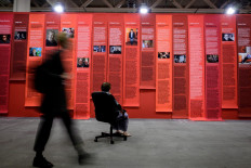 A visitor seats facing an artwork by Andrea Bowers entitled 'Open Secret' during a preview day of Art Basel, the world's premier modern and contemporary art fair, in Basel on June 12, 2019. 