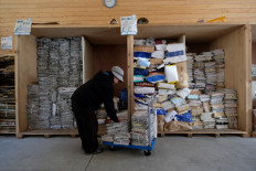 This picture taken on March 14, 2019 shows a worker sorting newspapers and magazines for recycling at a waste center in the town of Kamikatsu, Tokushima prefecture.
