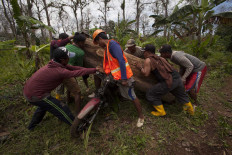 Eight men load teakwood onto a motorcycle. JP/Sigit Pamungkas