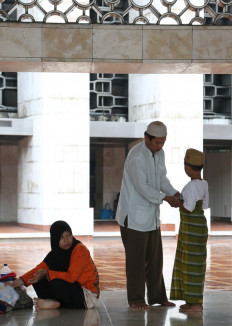 A man helps his son put on a sarong prior to performing prayers at Istiqlal Mosque in Central Jakarta in this file photo. 